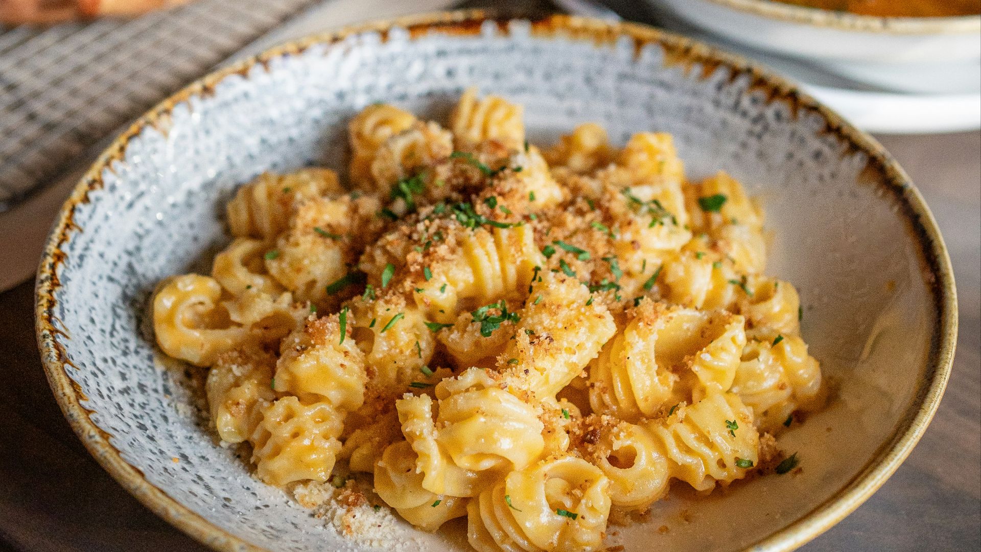 a bowl of pasta and a plate of pizza on a table