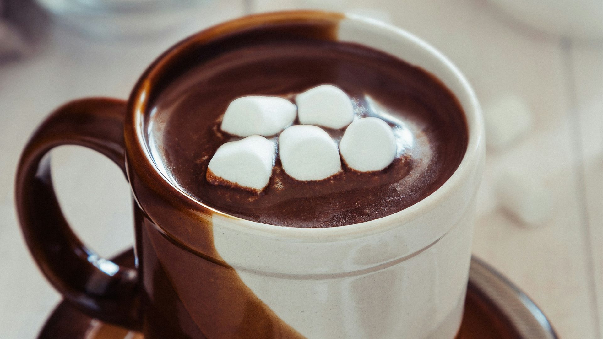 a cup of hot chocolate with marshmallows on a saucer