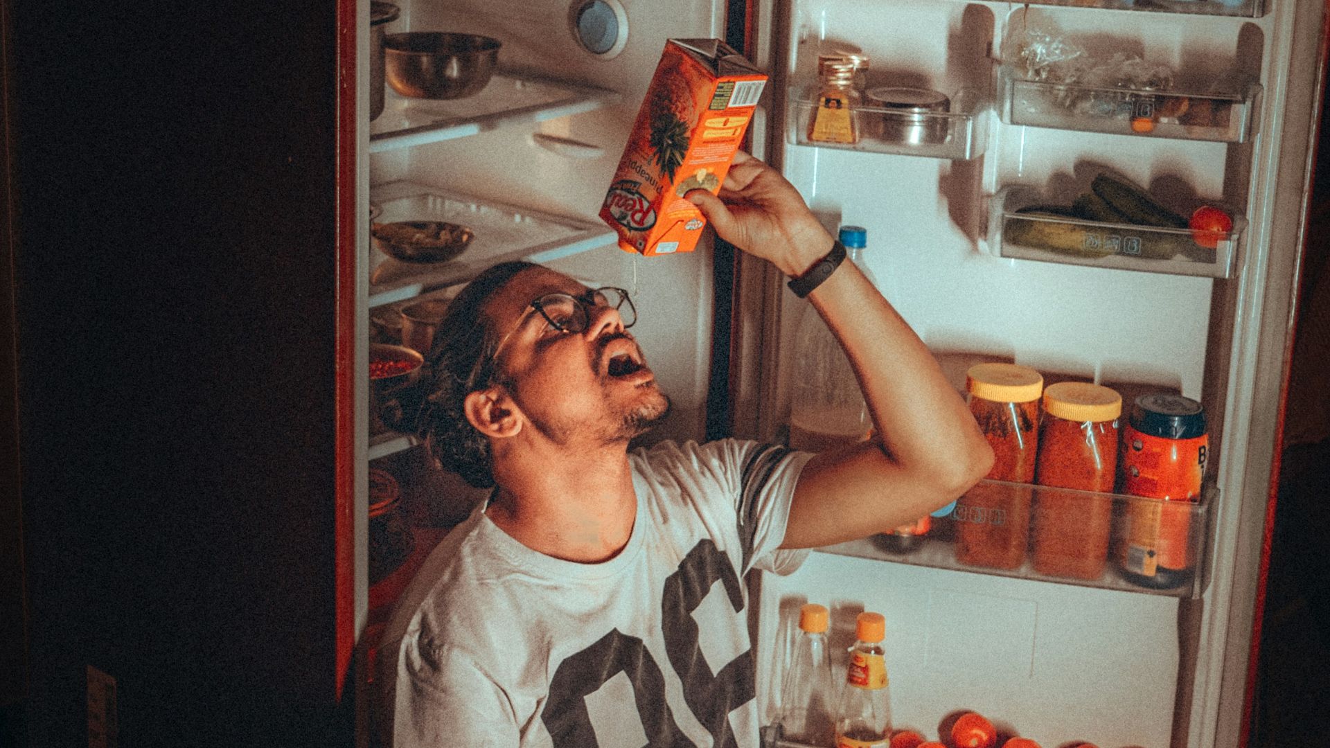 boy in white and black tank top standing beside red top mount refrigerator