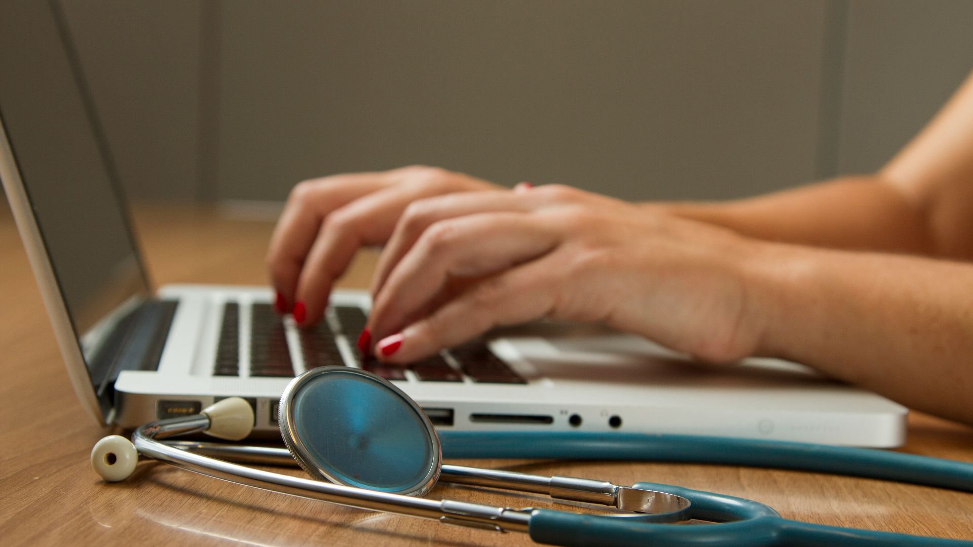 person sitting while using laptop computer and green stethoscope near