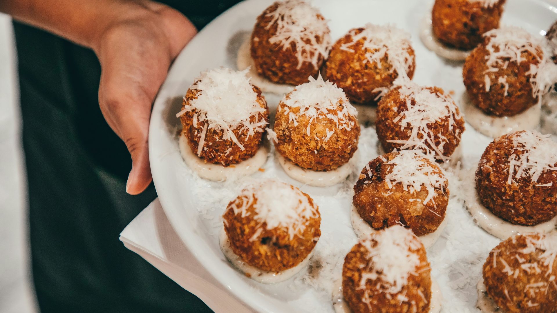 a person holding a plate of food with powdered sugar on it