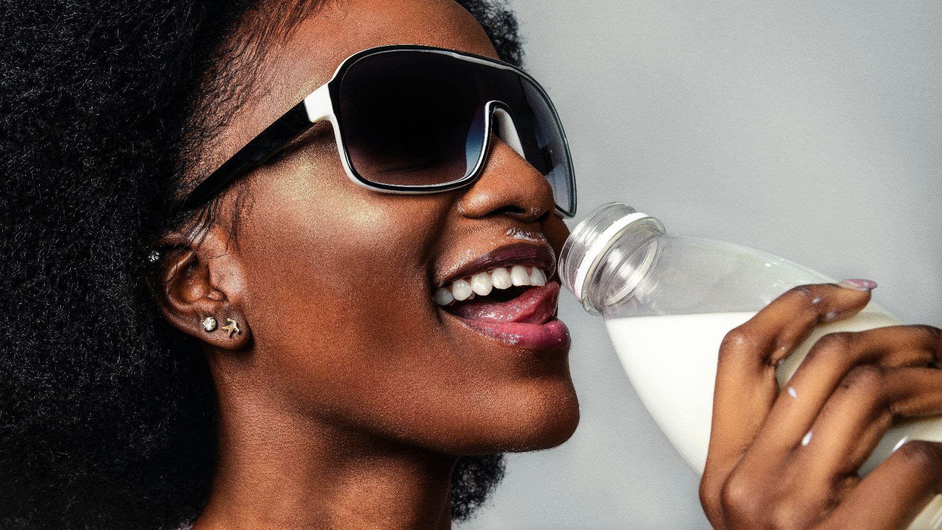 woman wearing black and white sunglasses drinking milk