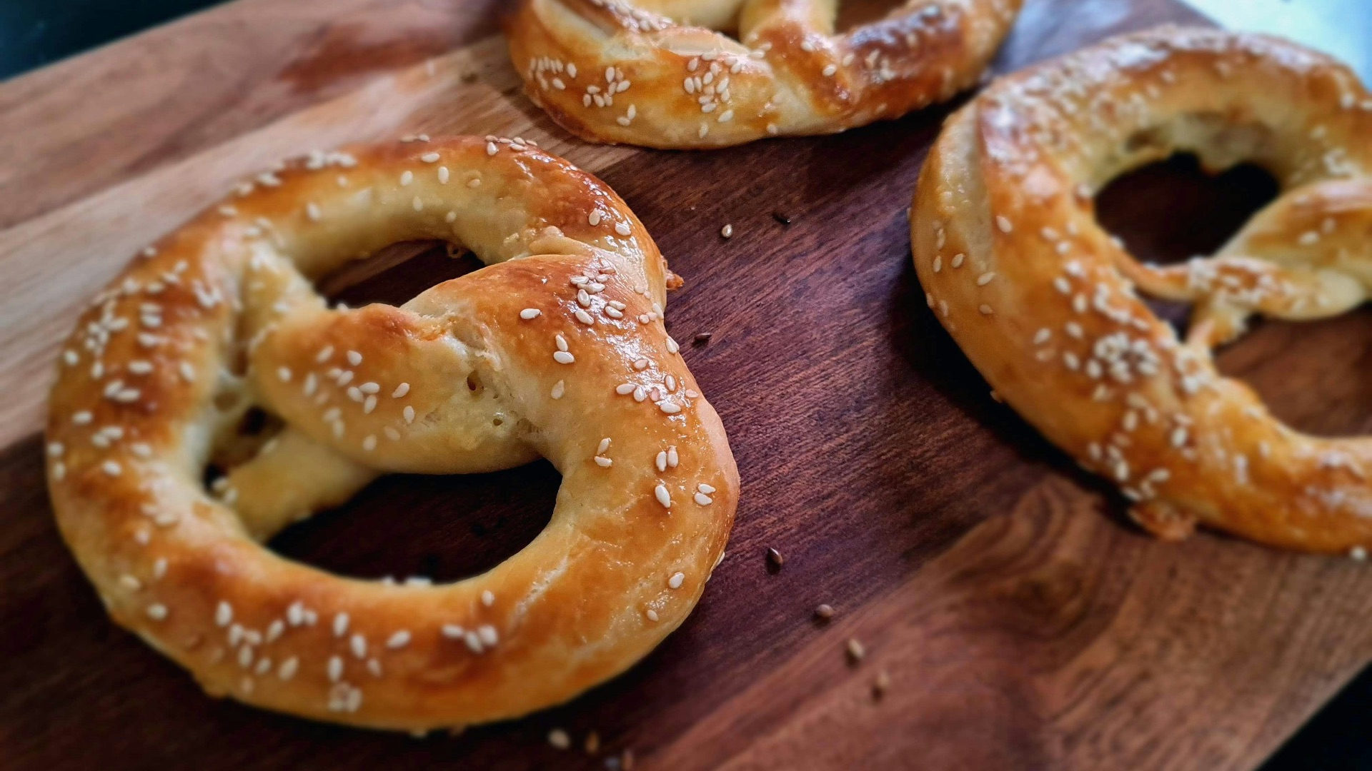 a wooden cutting board topped with three pretzels