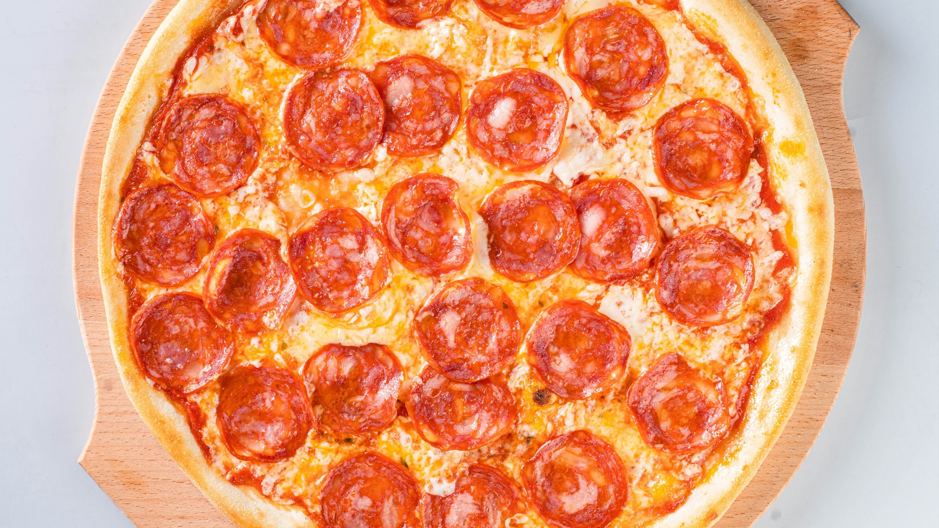 a pepperoni pizza sitting on top of a wooden cutting board