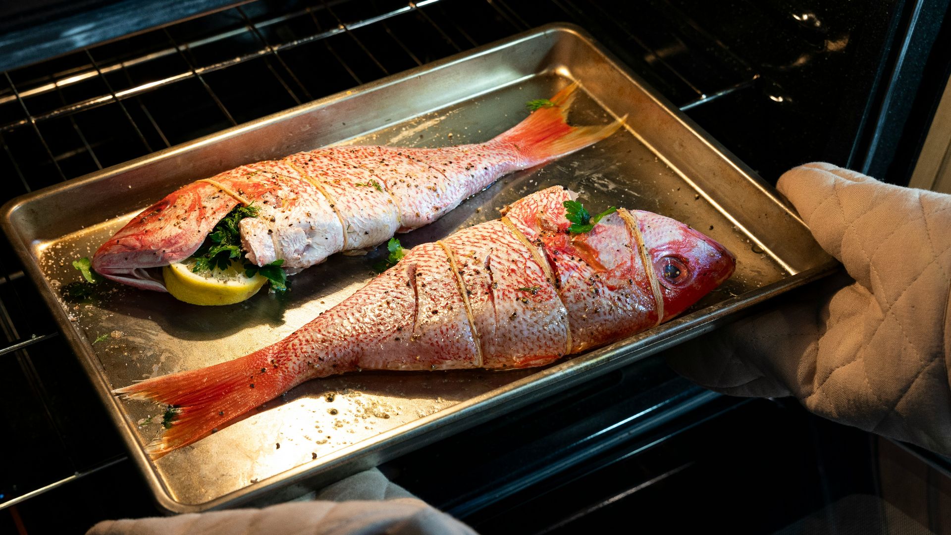 a person pulling a fish out of an oven