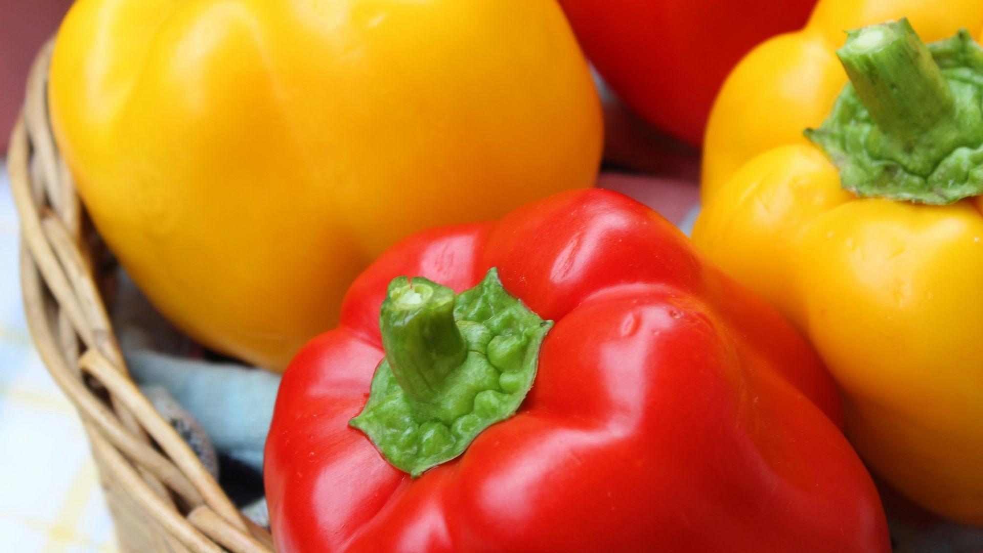 red and yellow bell peppers in brown woven basket