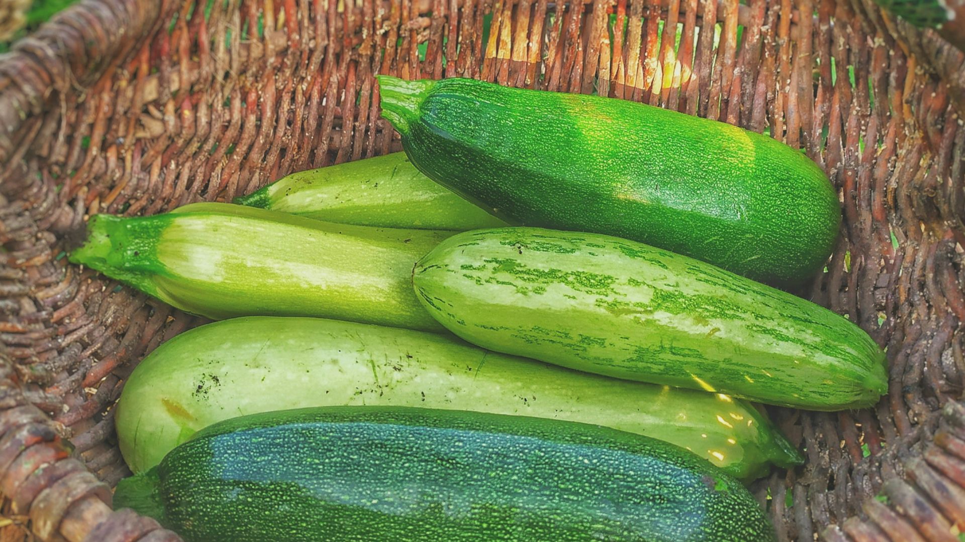 green cucumbers on round brown wicker basket
