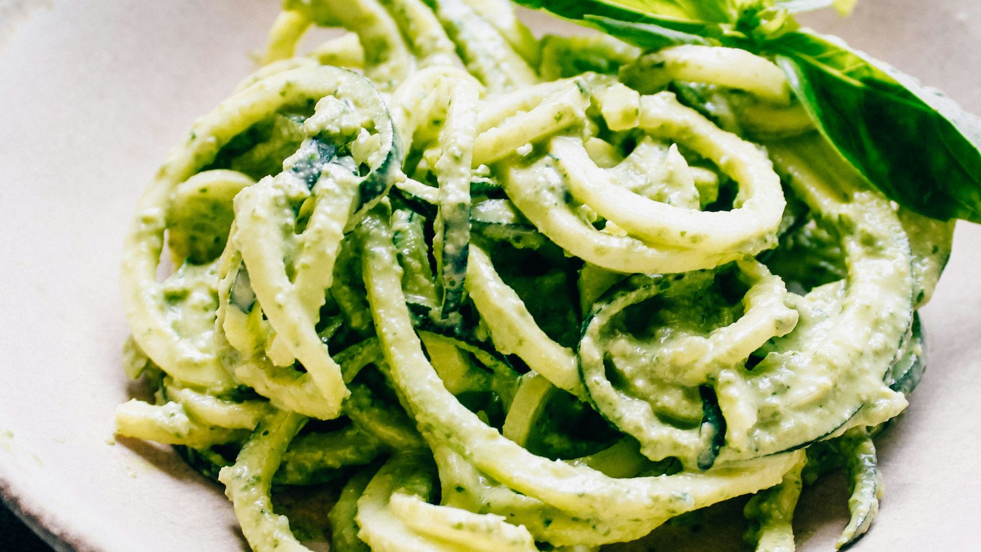 a white bowl filled with pesto pasta on top of a table