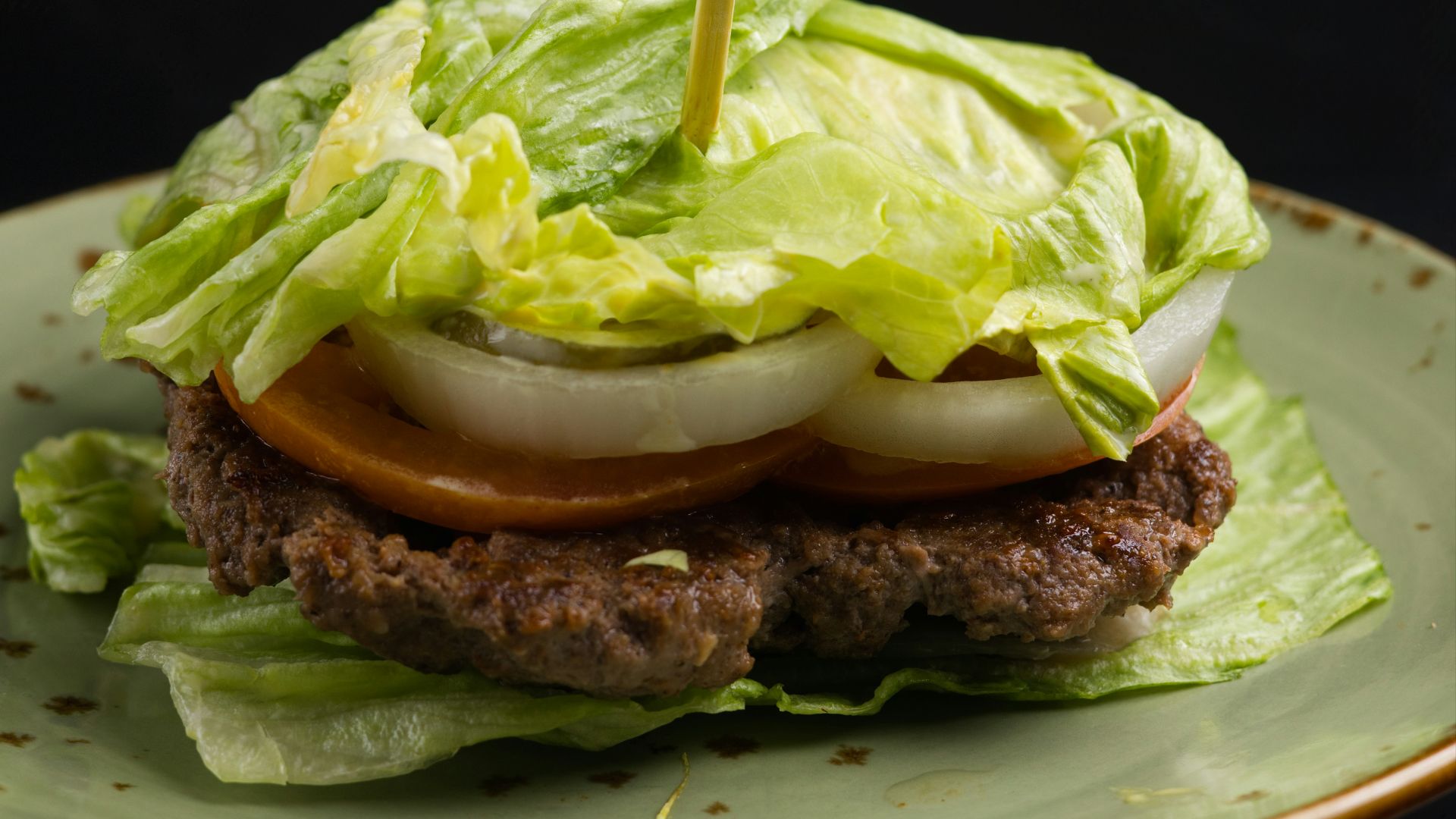 A lettuce-wrapped burger with tomato and onion