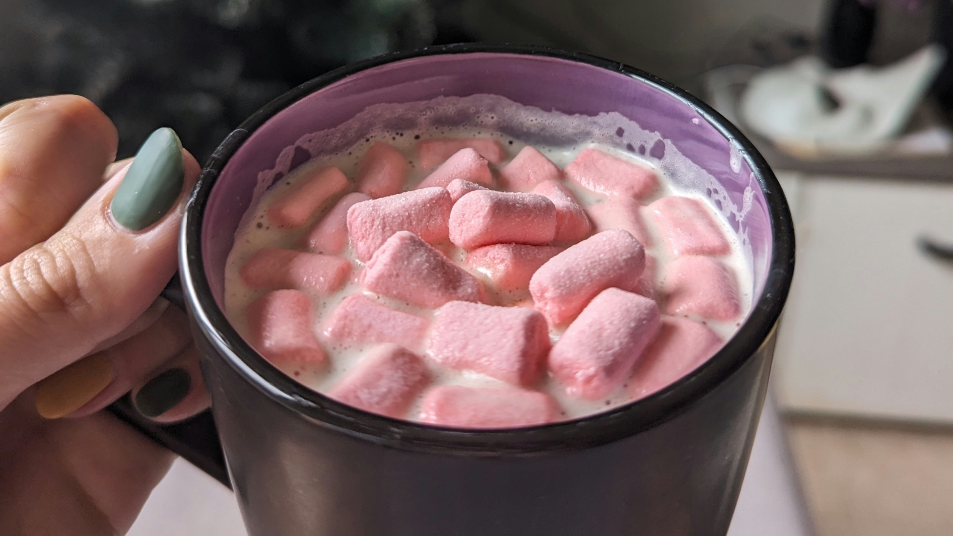 A woman holding a cup of hot chocolate with marshmallows