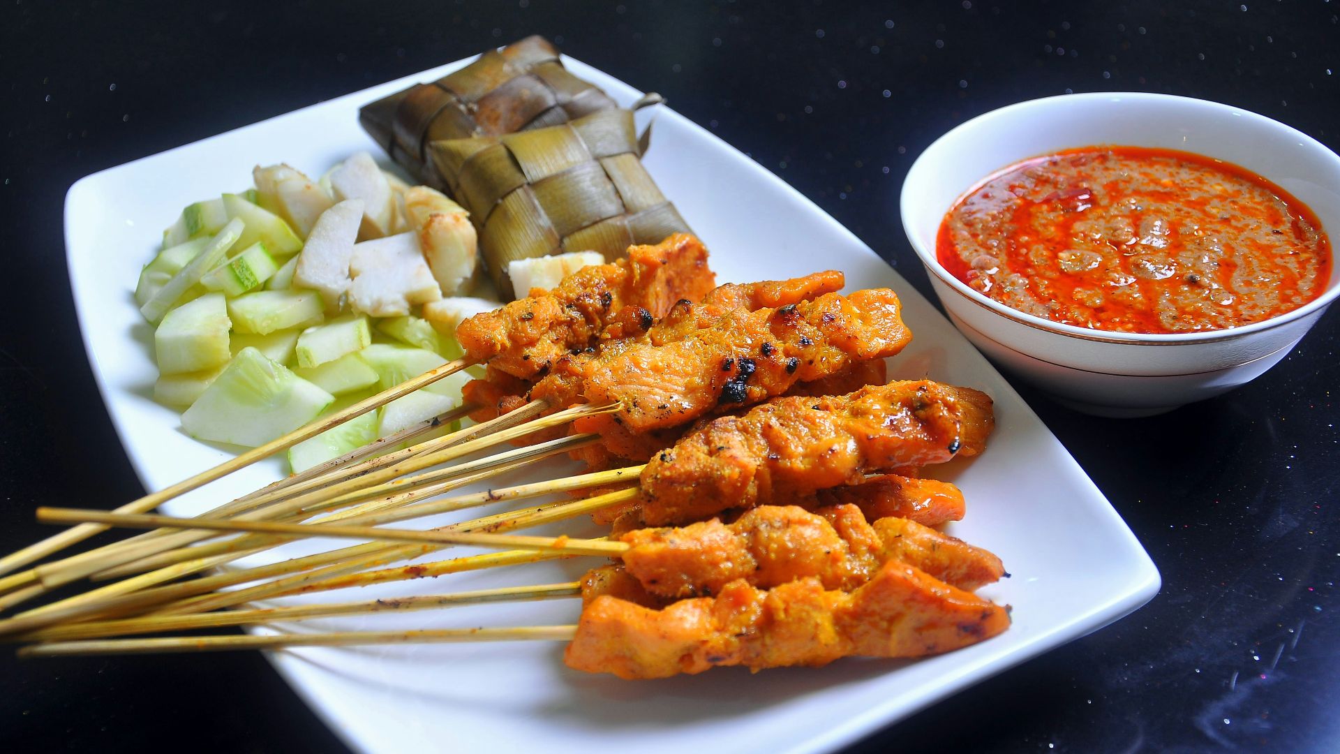 a white plate topped with meat and veggies next to a bowl of sauce