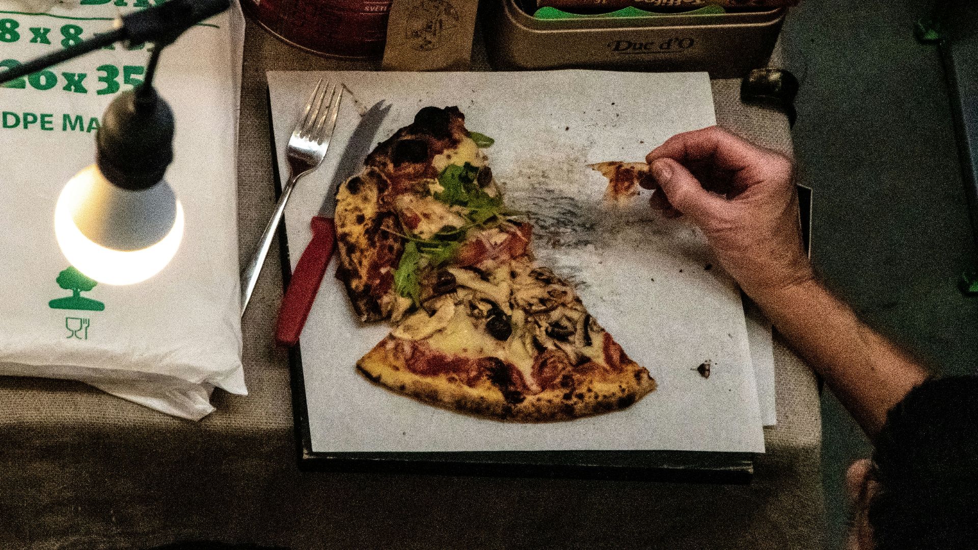 a person eating a slice of pizza from a box