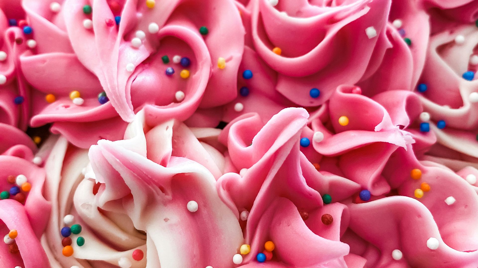 a close up of a pink cake with sprinkles