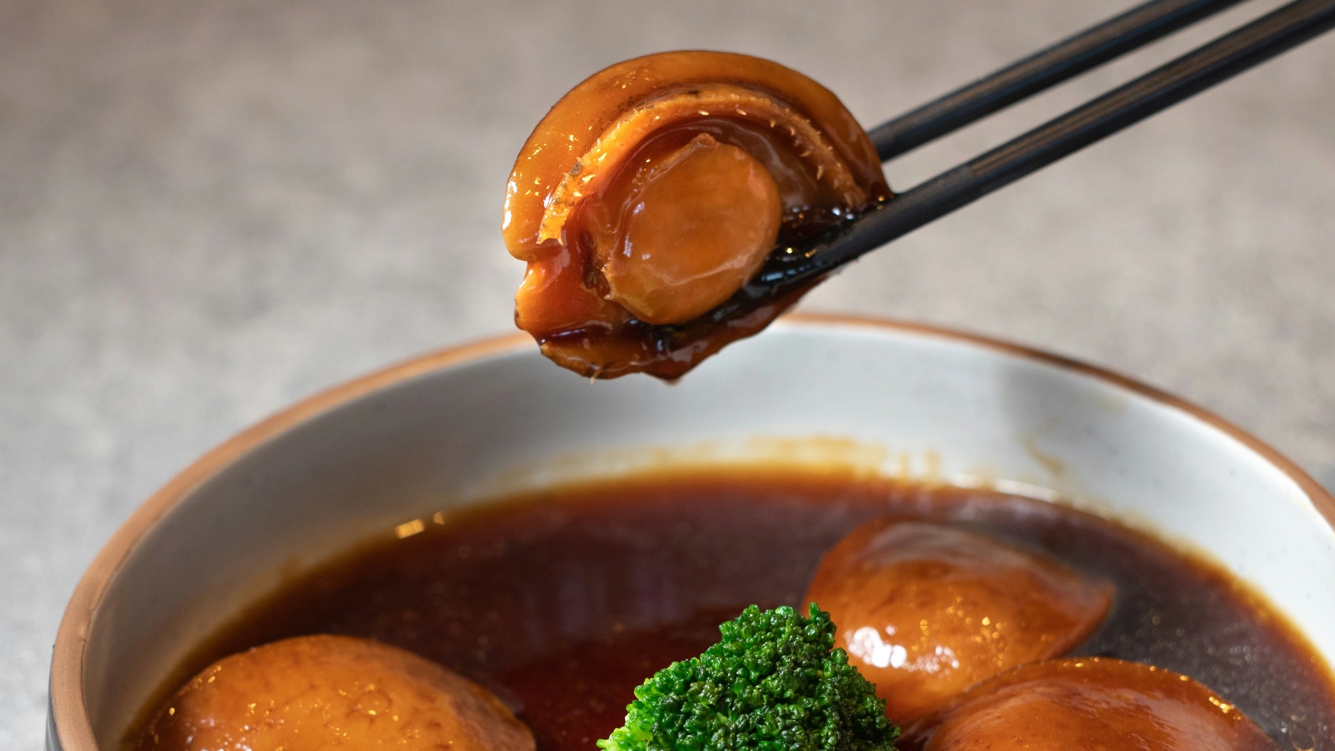 a bowl of soup with broccoli and chopsticks
