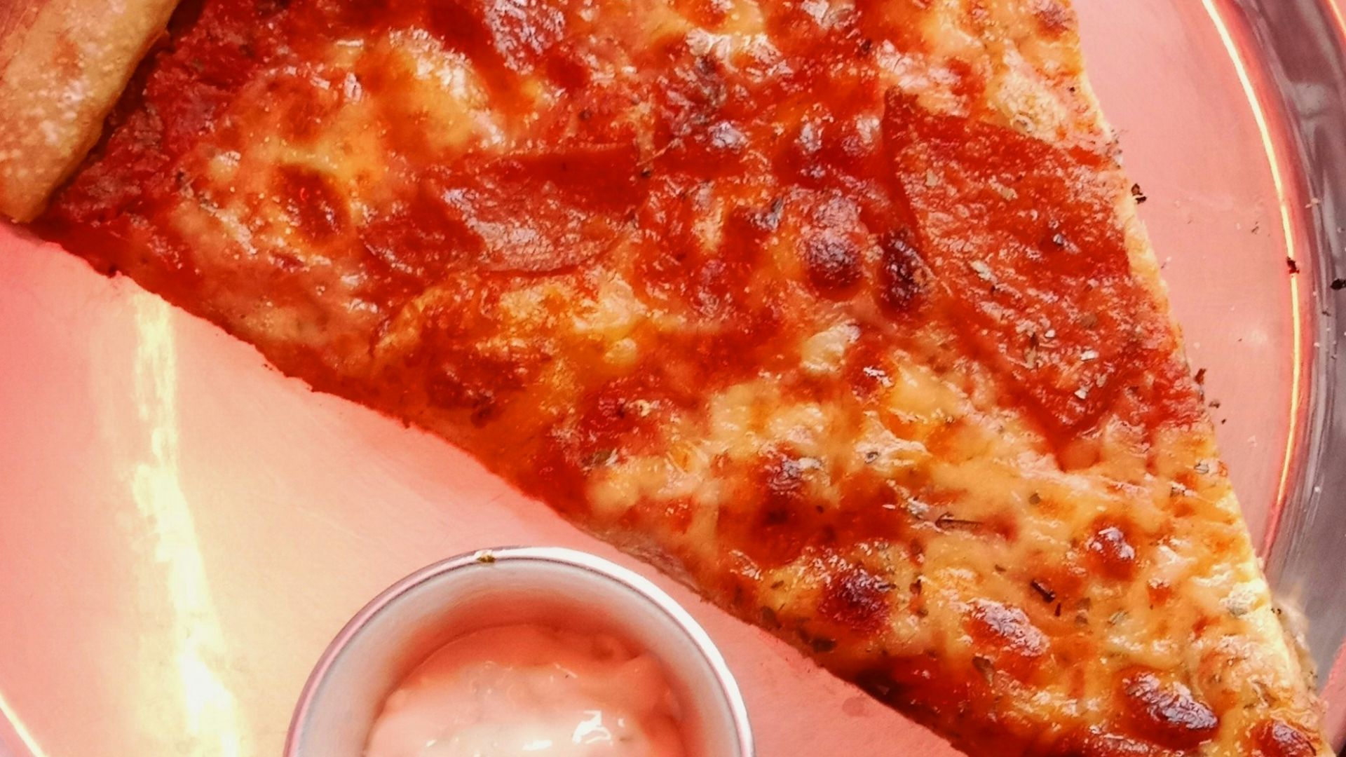 a slice of pizza on a pink plate