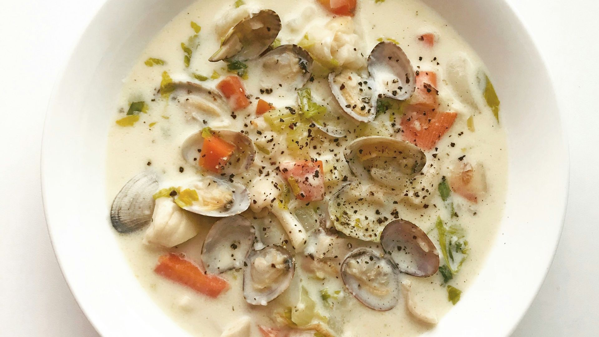 clam and vegetable soup in white ceramic bowl