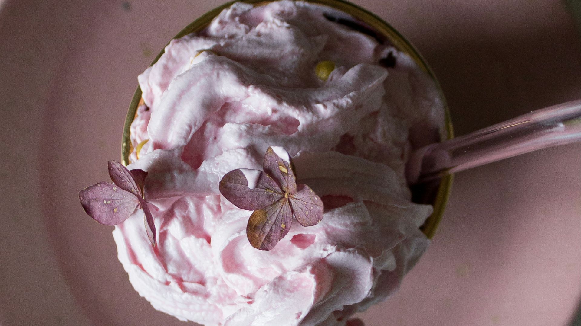 Pink dessert with edible flowers on a pink plate.