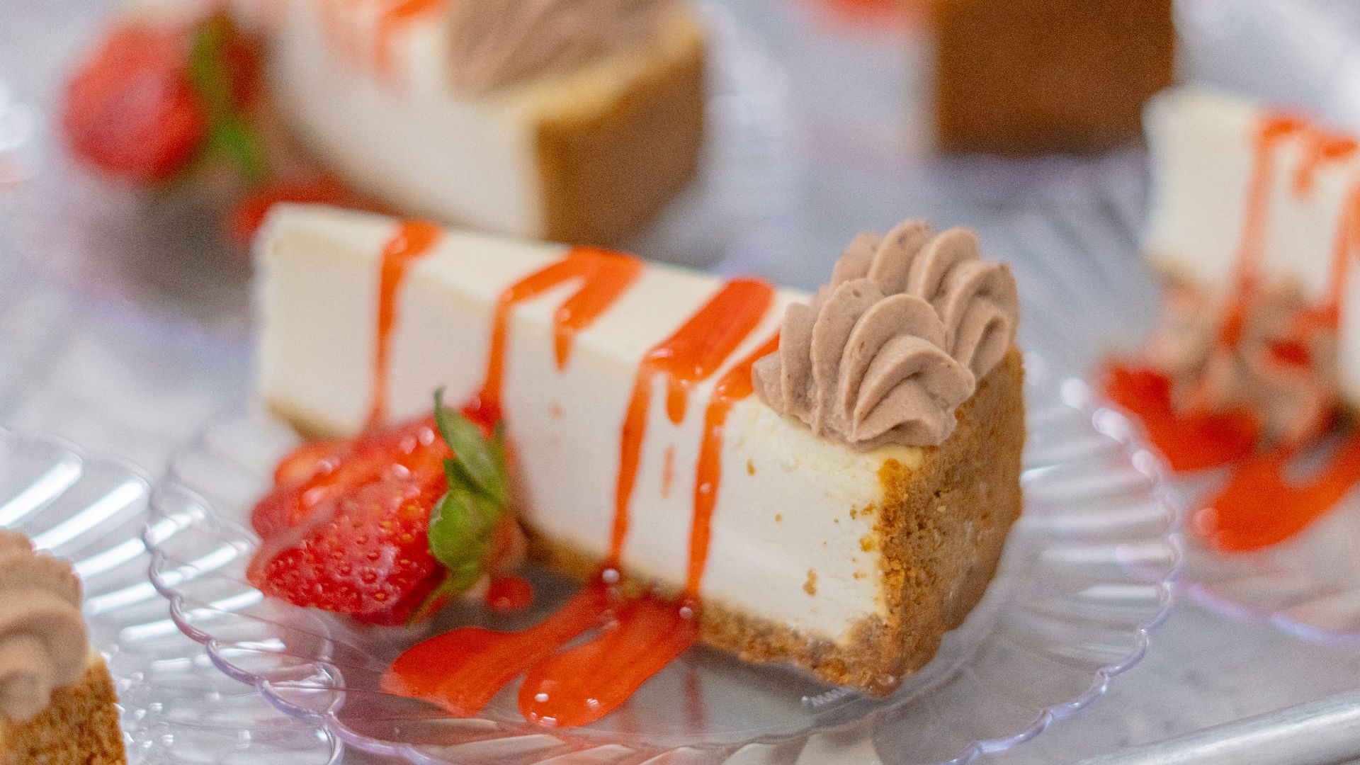Cheesecake slices with strawberries and sauce are displayed.