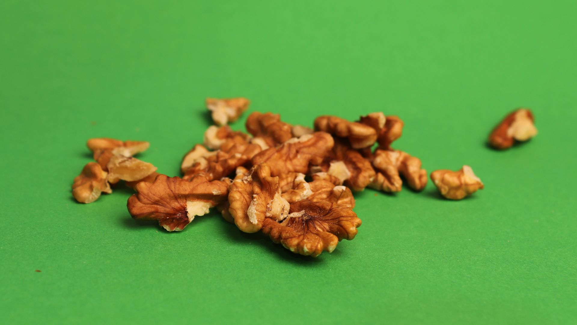 A pile of walnuts sitting on top of a green table
