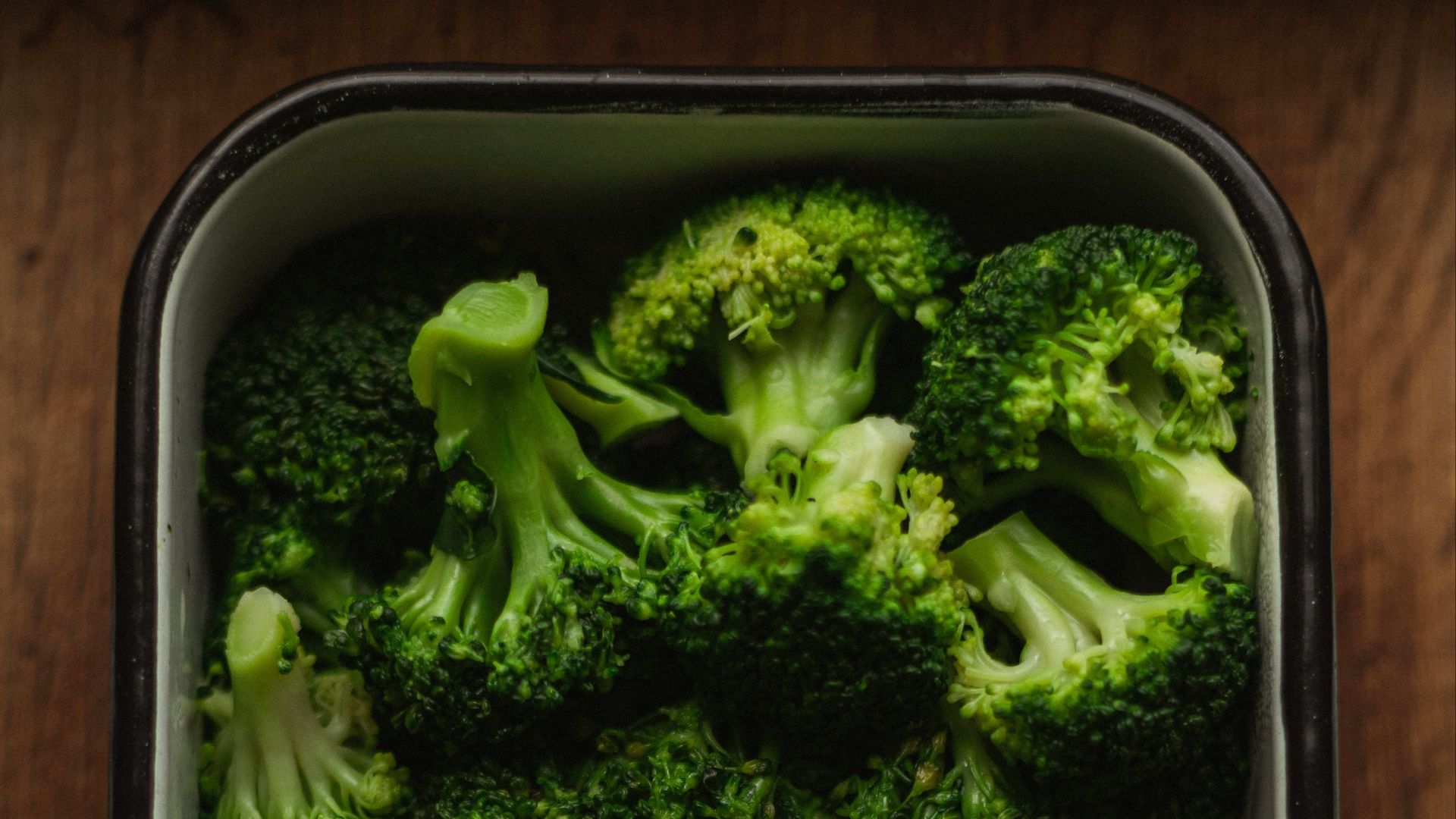 a dish of broccoli on a wooden table