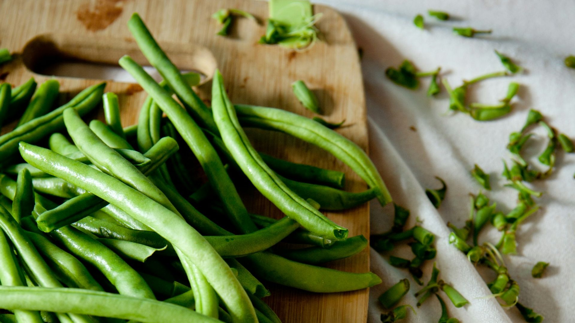 green peas on top of brown wooden chopping board