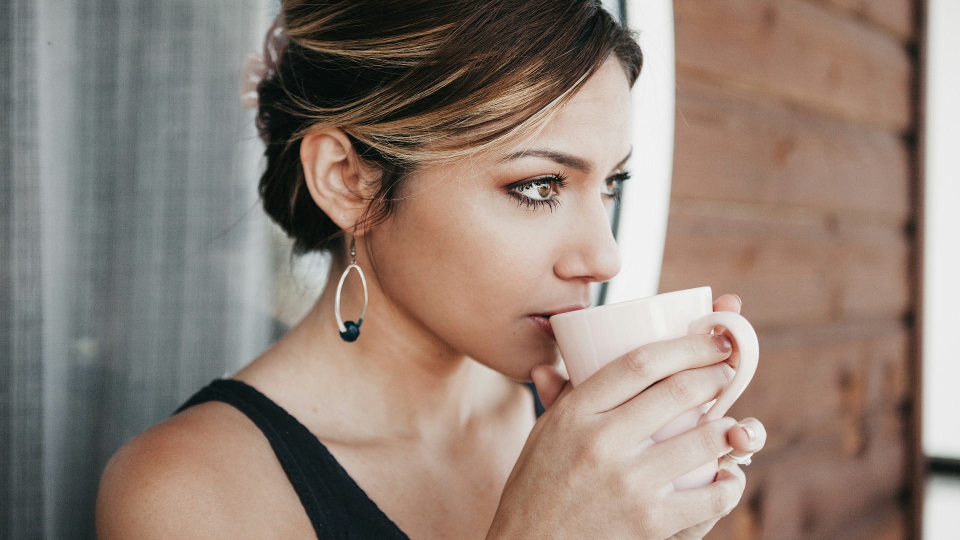woman leaning on wall drinking coffee