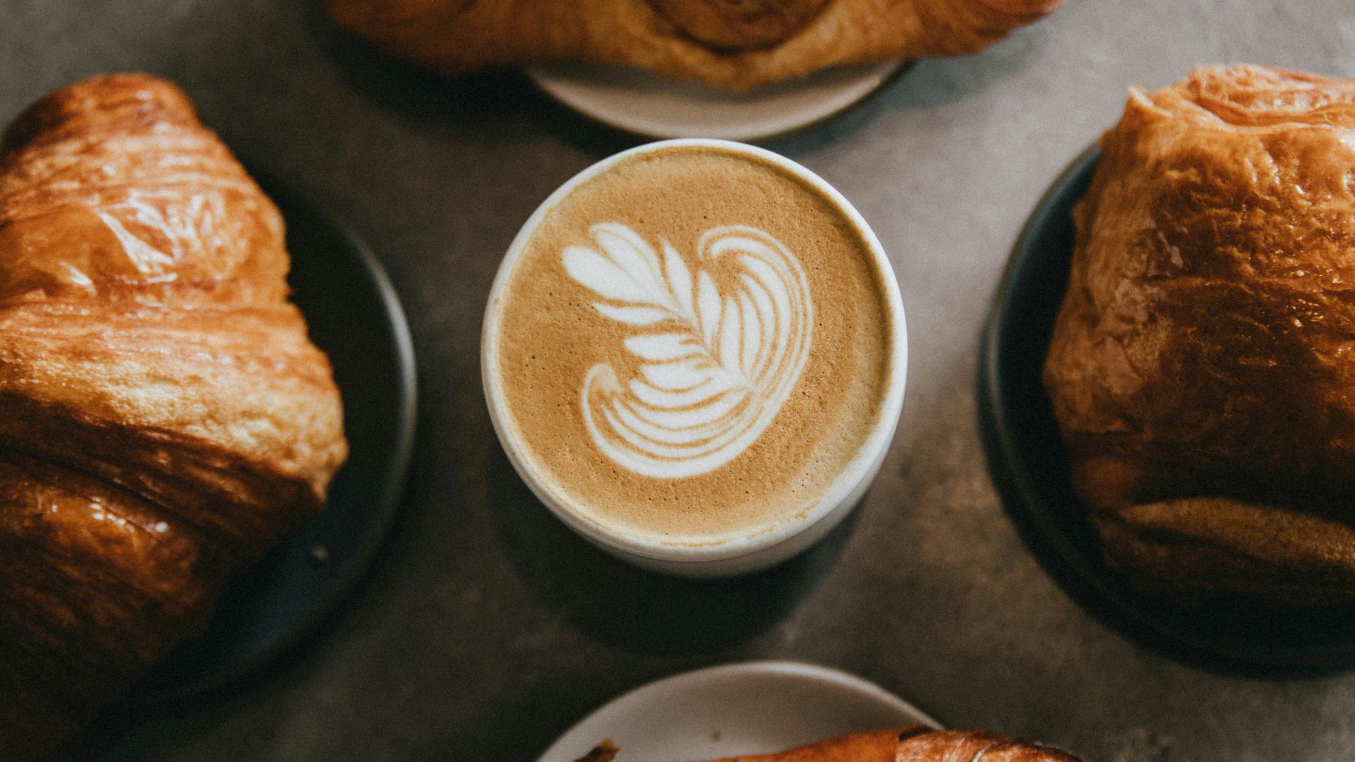 coffee surrounded by four baked breads