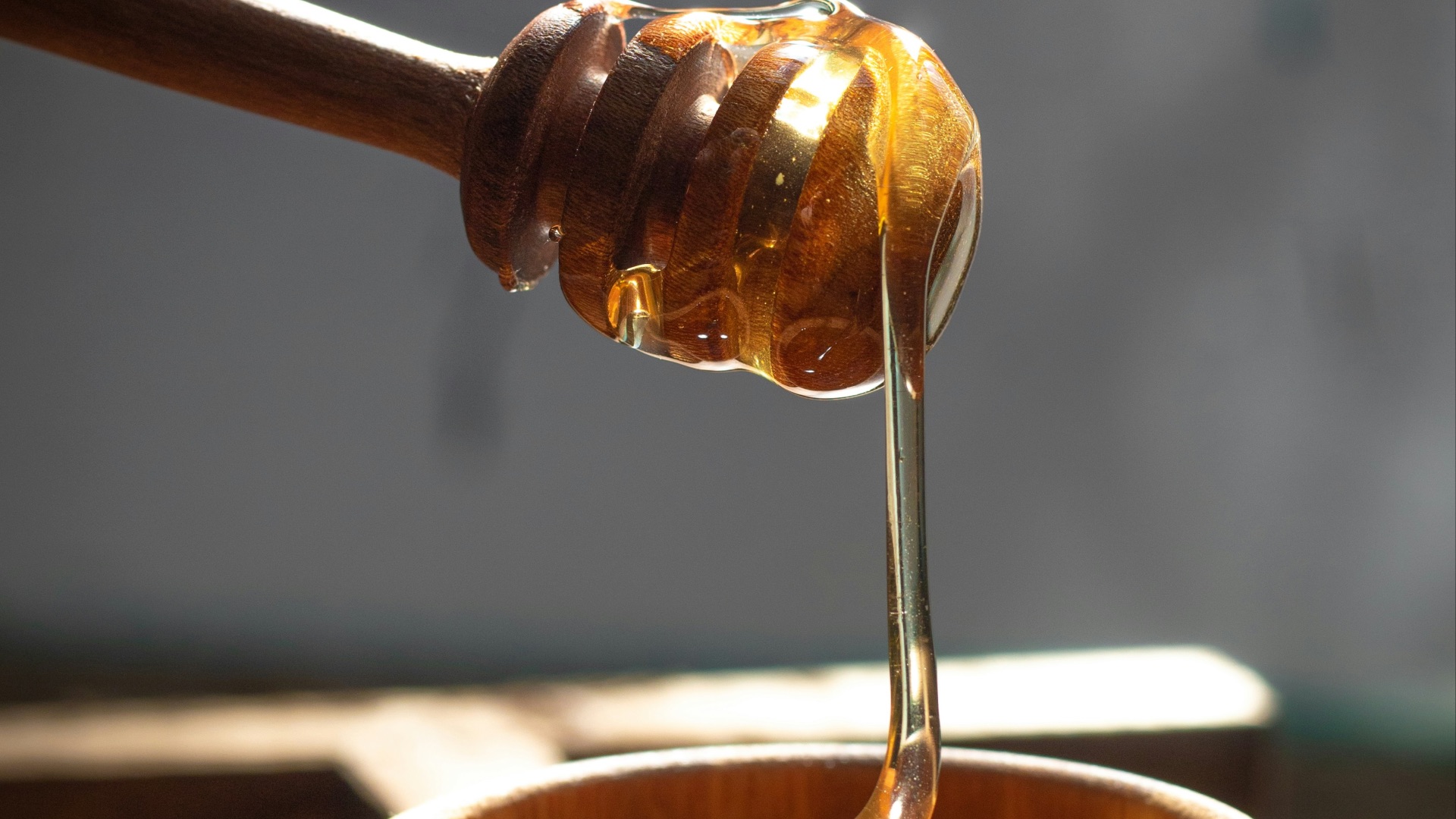 a honey dip being poured into a wooden bowl