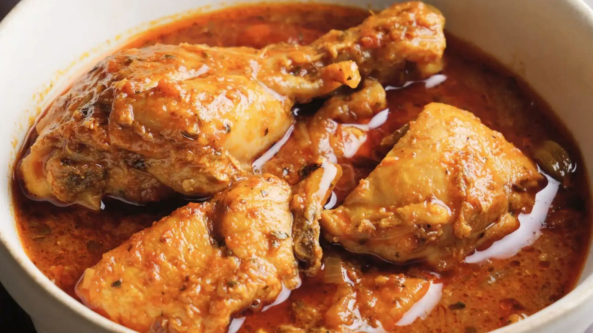 Chicken curry in a white bowl with sauce.