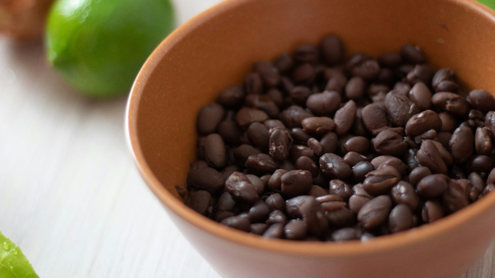 a bowl filled with black beans next to limes