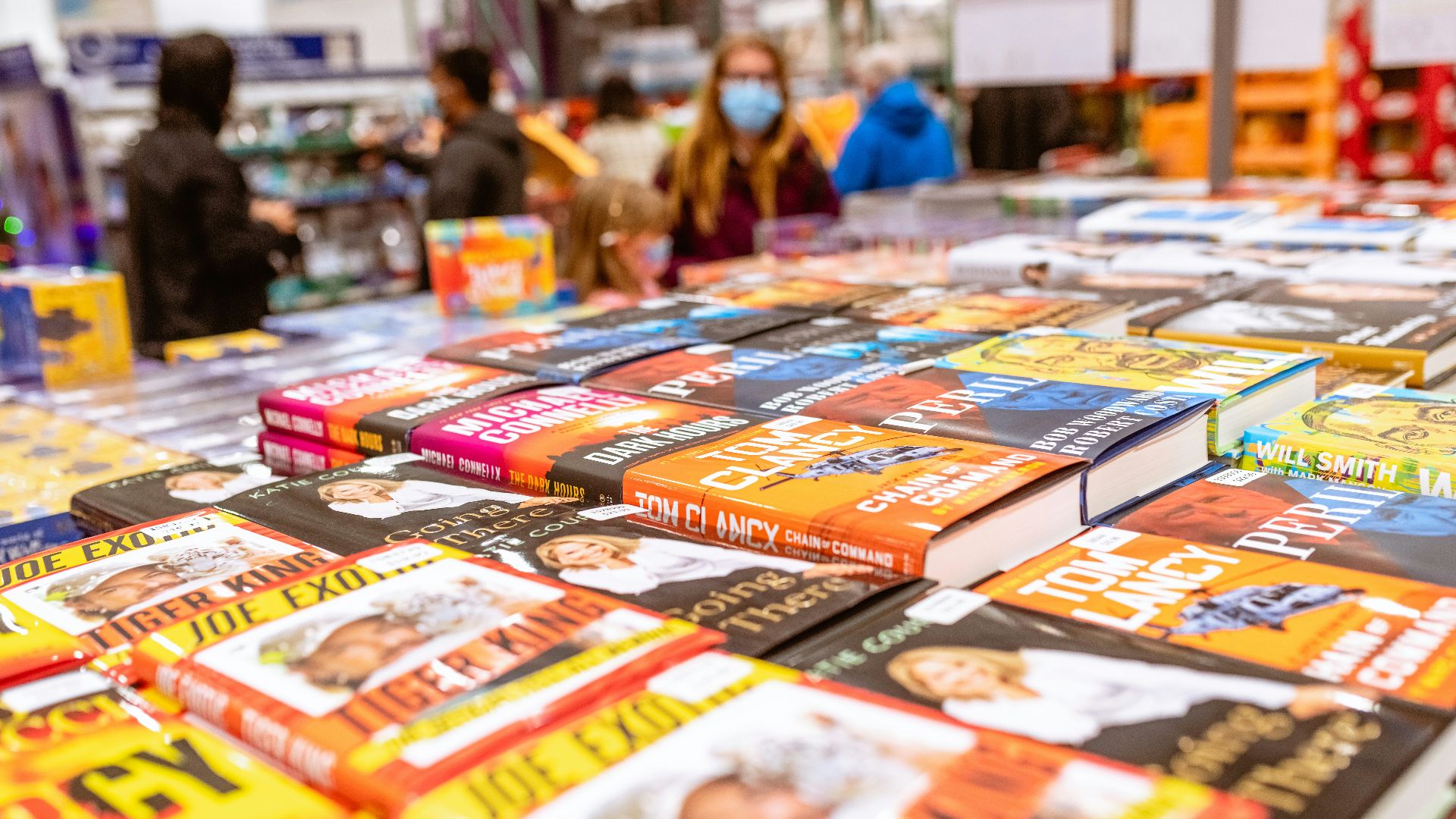 a table full of children's books with people in the background