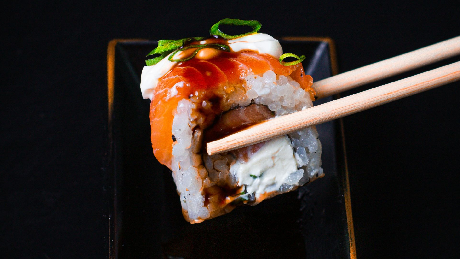 a black plate topped with sushi and chopsticks