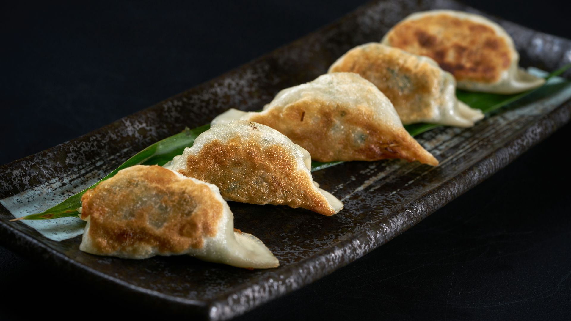 a black plate topped with three dumplings of food