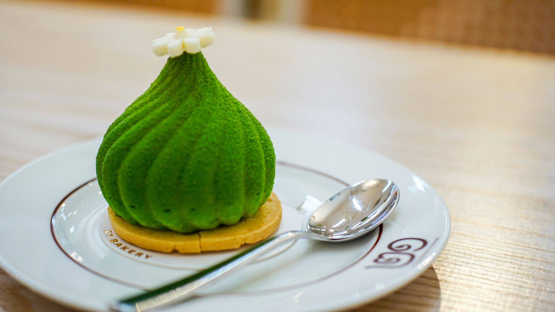 A green dessert with white flower topping on plate.
