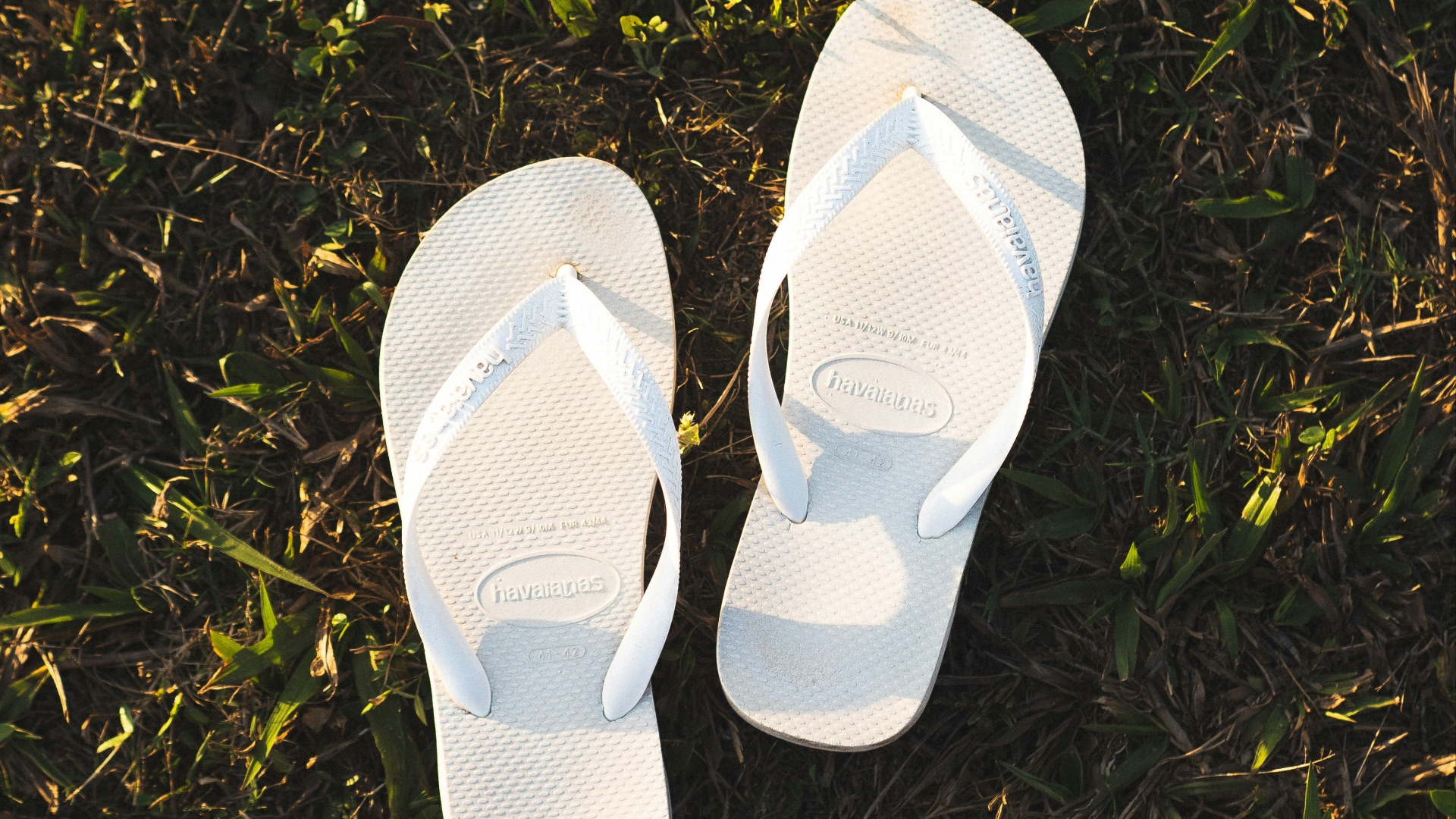 a pair of white slippers sitting on top of a lush green field