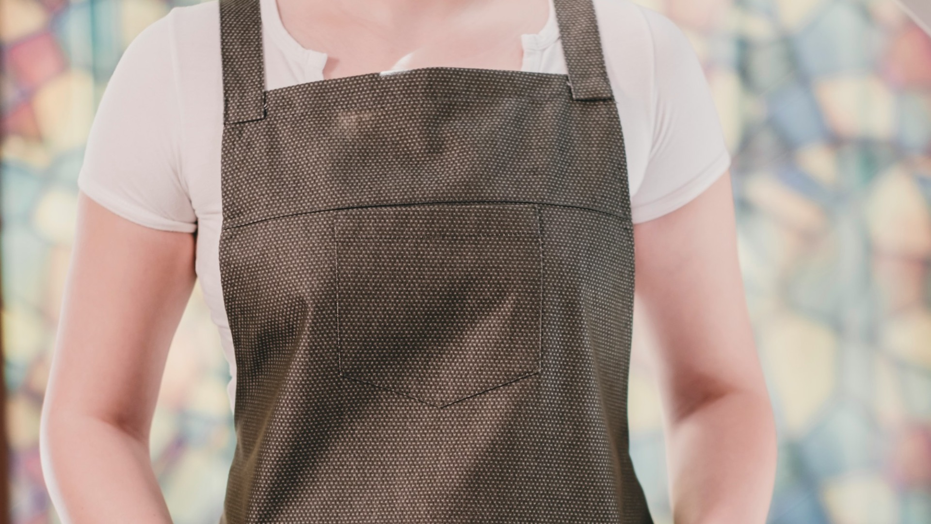 A woman wearing an apron standing in front of a stained glass window