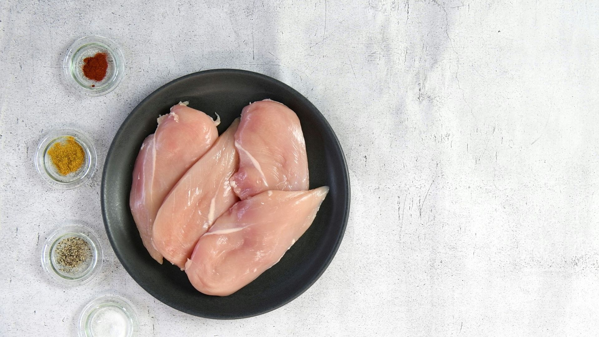 two raw chicken breasts in a black bowl