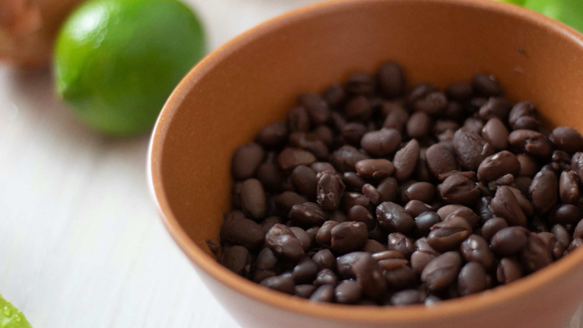 a bowl filled with black beans next to limes