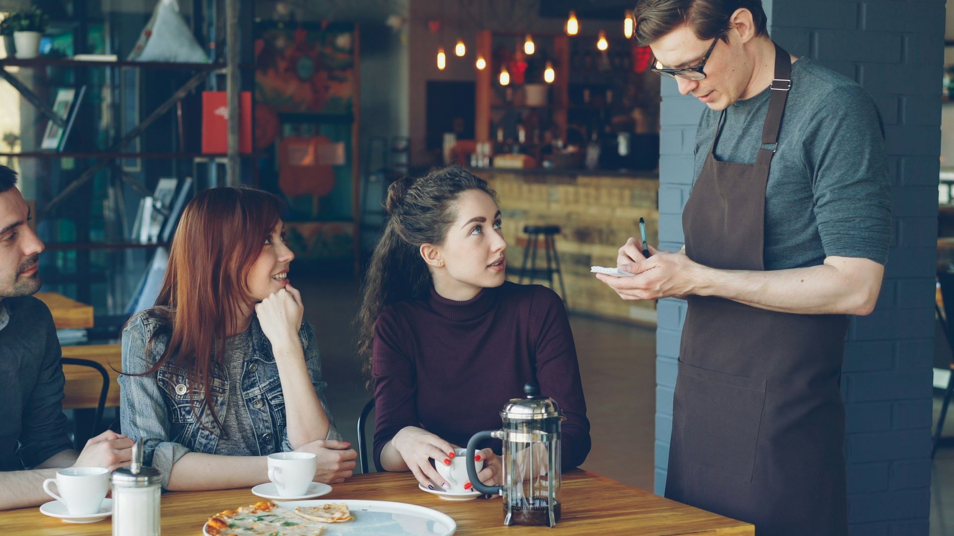 A waiter takes an order from customers at a cafe.