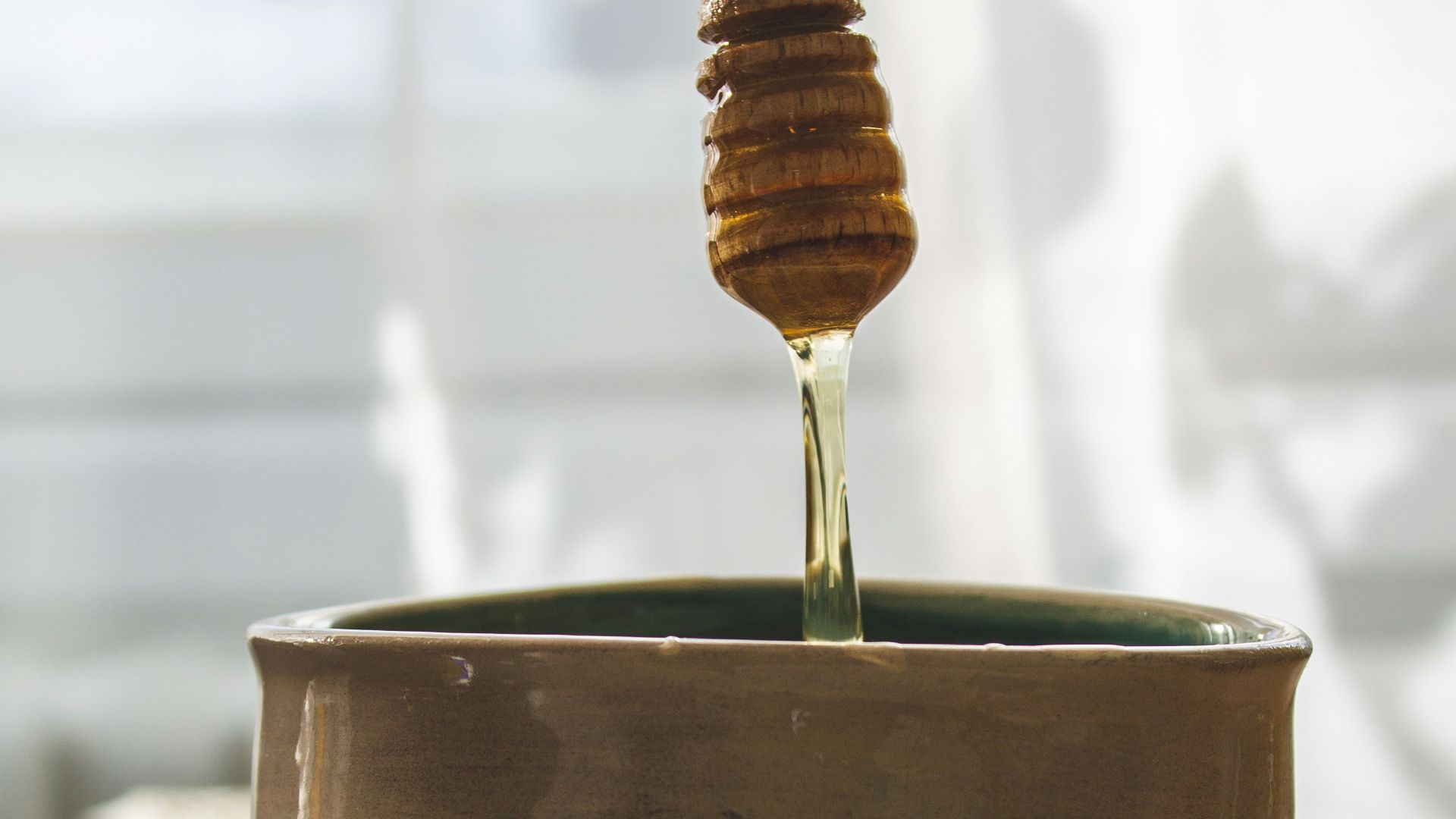 a spoon is pouring honey into a bowl