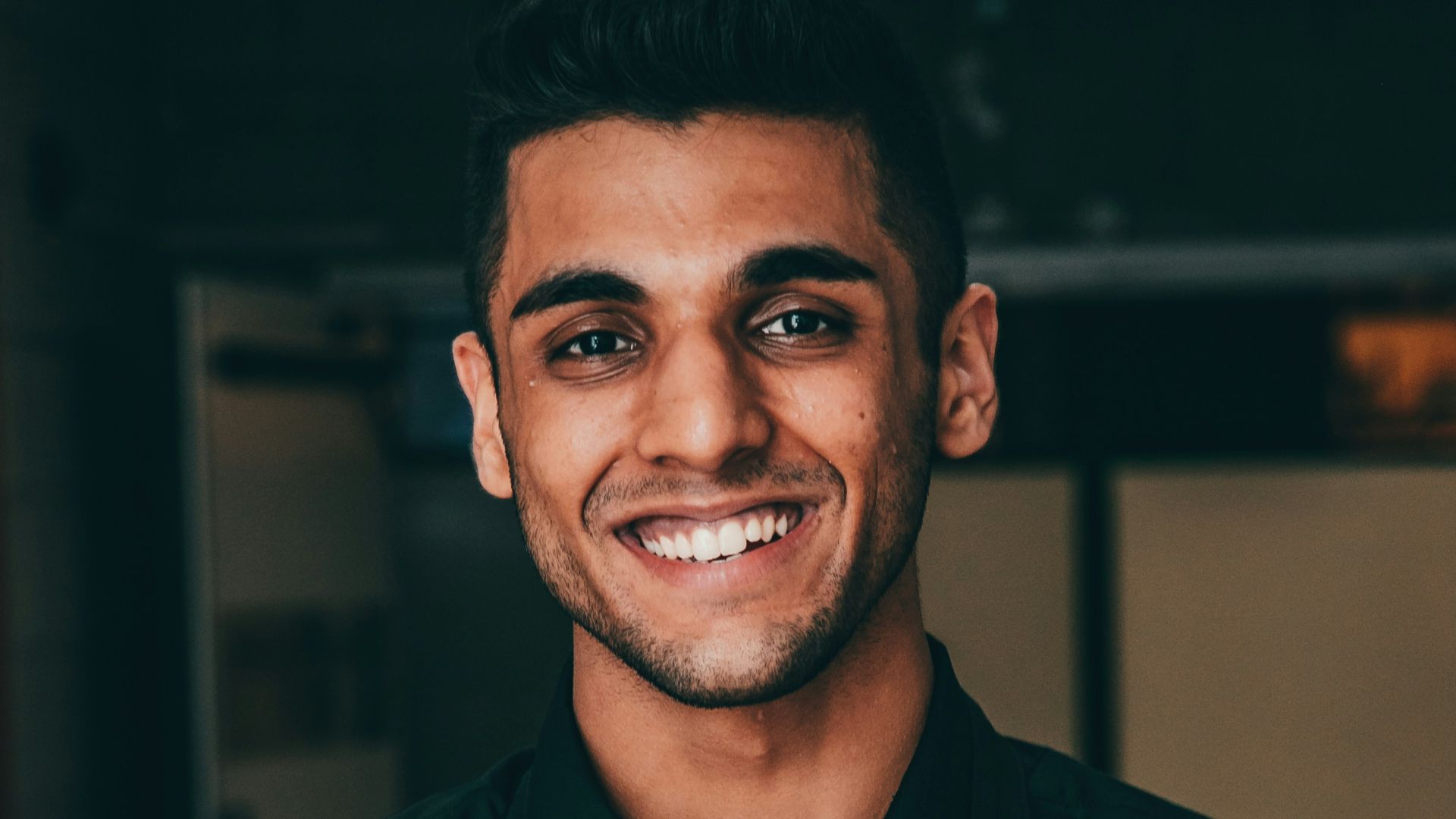 a man in a black shirt is holding a pizza