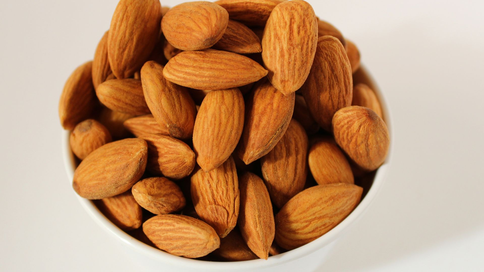 brown almond nuts on white ceramic bowl