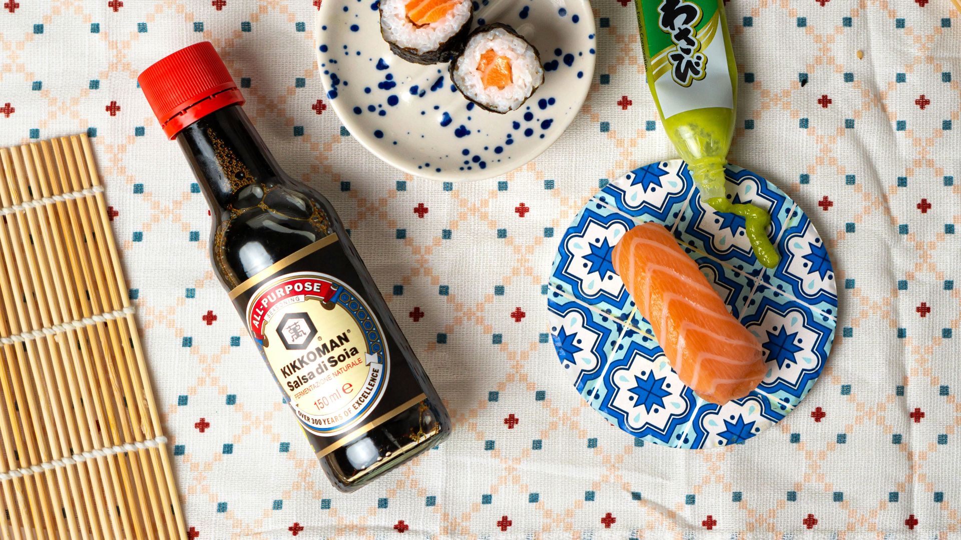 a table topped with a plate of sushi and a bottle of sauce