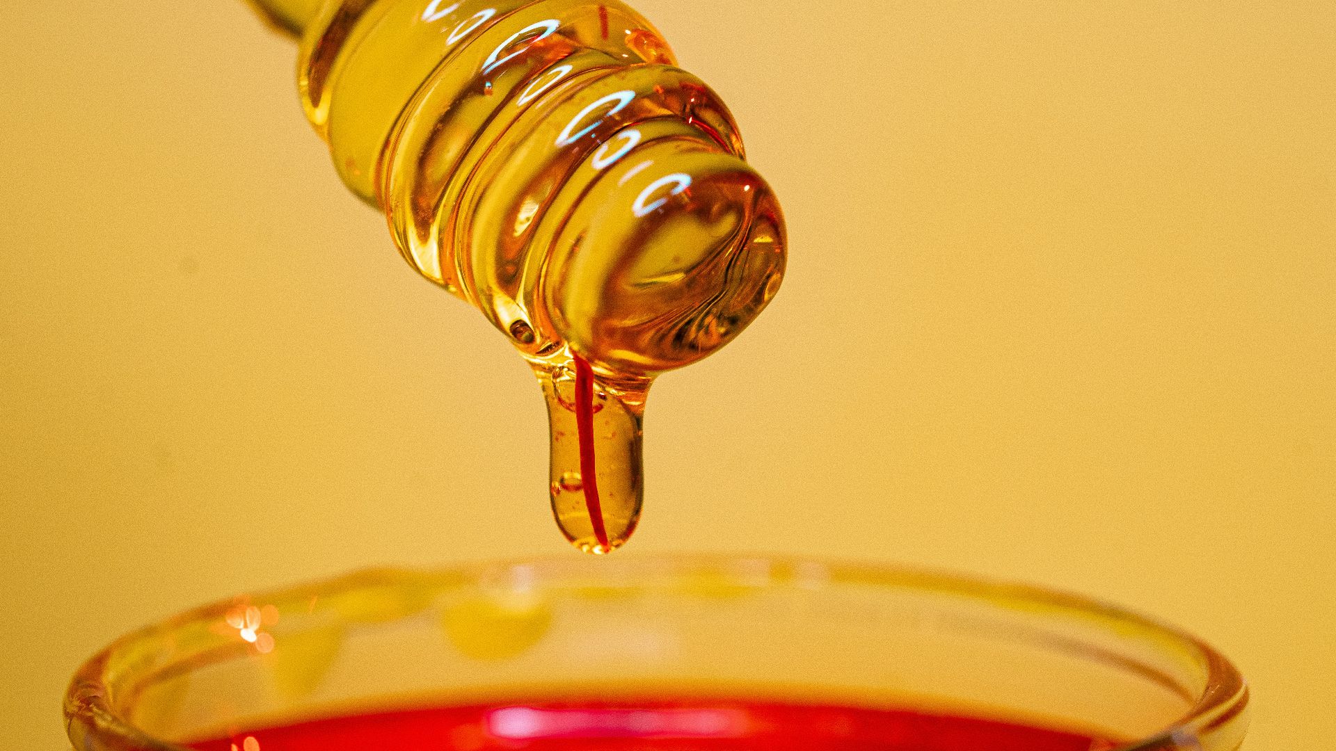 clear glass bottle pouring red liquid on clear drinking glass