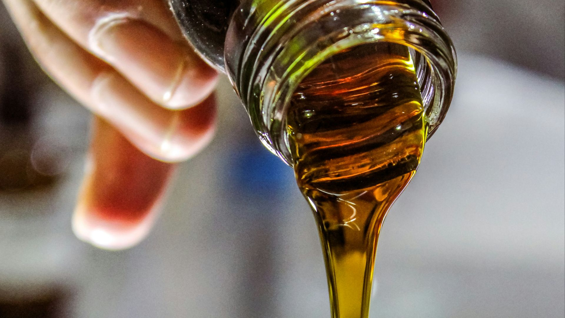 person holding clear drinking glass with brown liquid