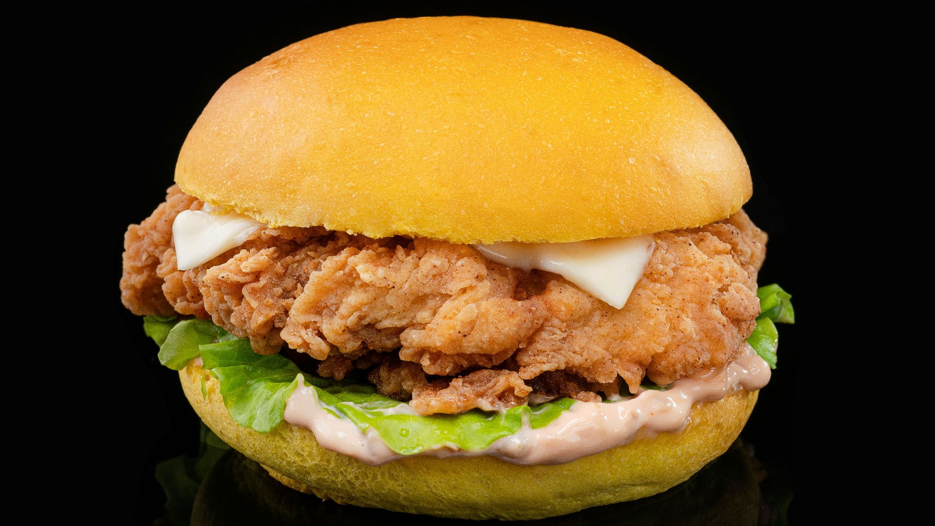 a chicken sandwich with lettuce and mayonnaise on a black background
