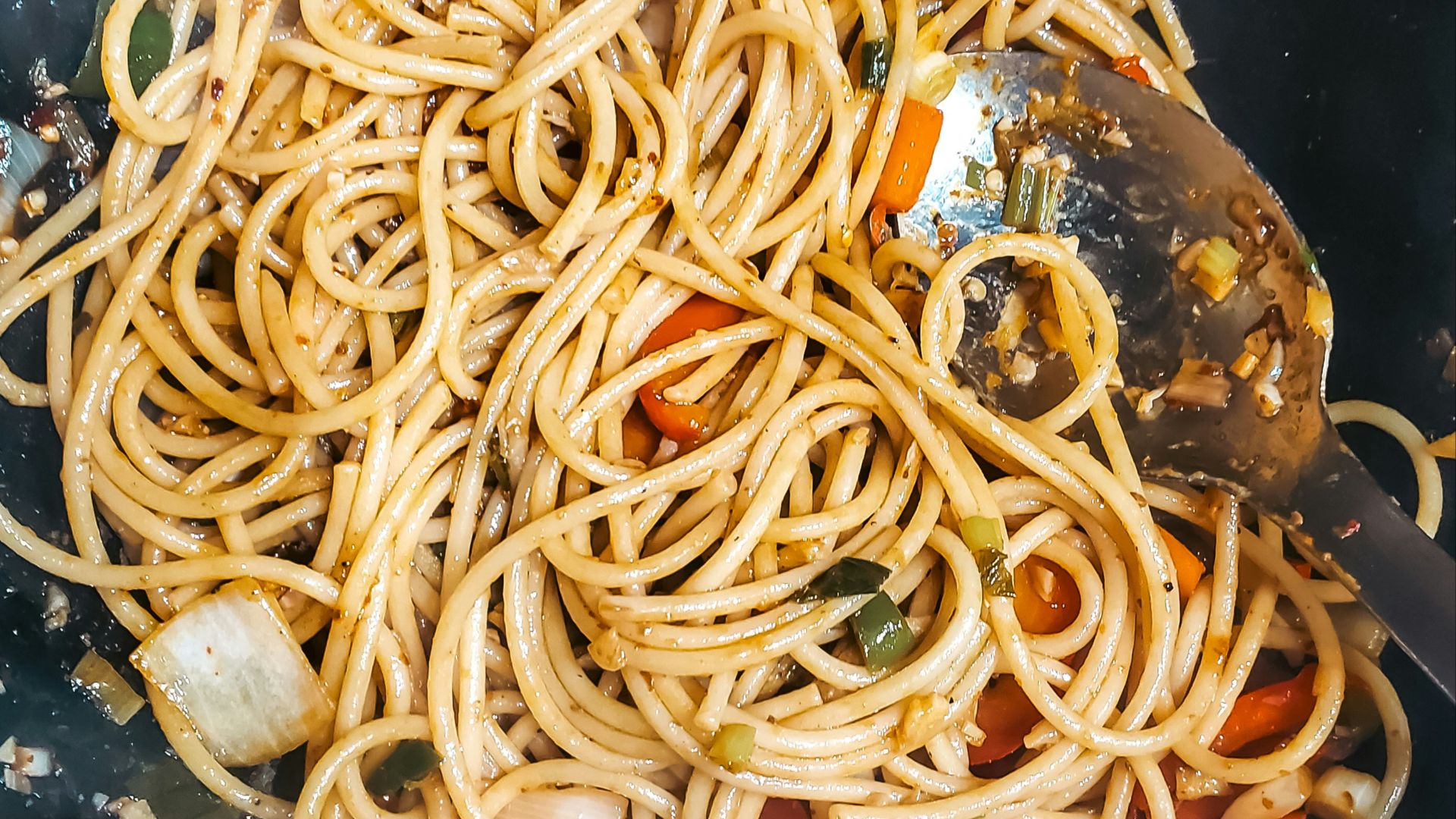Pasta and vegetables are cooking in a wok.