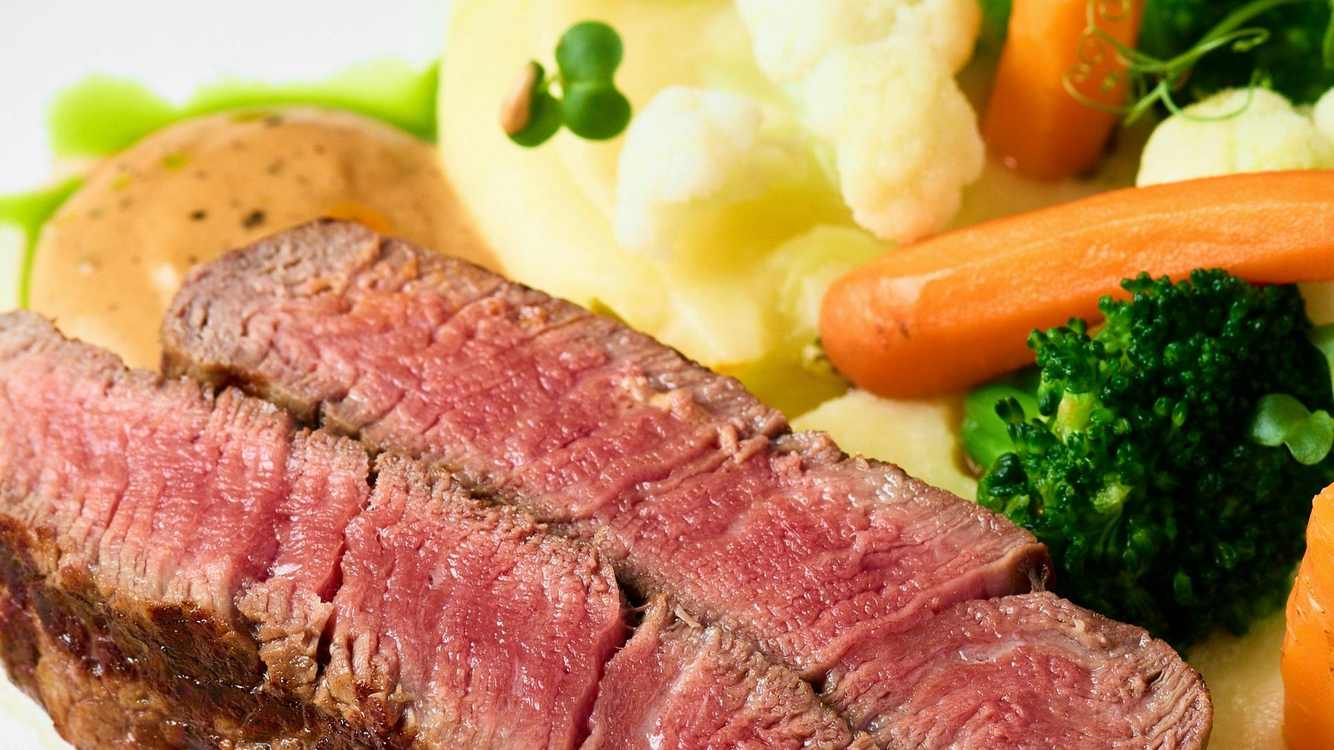Medium-rare steak served with colorful vegetables.