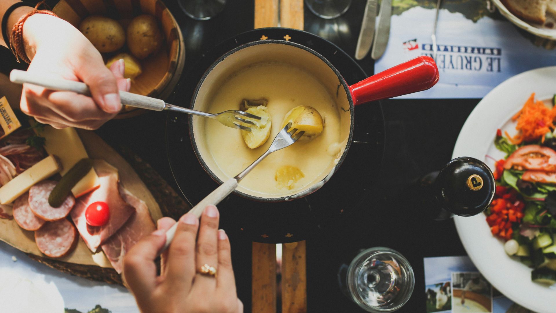 two person holding fork dipping food on sauce