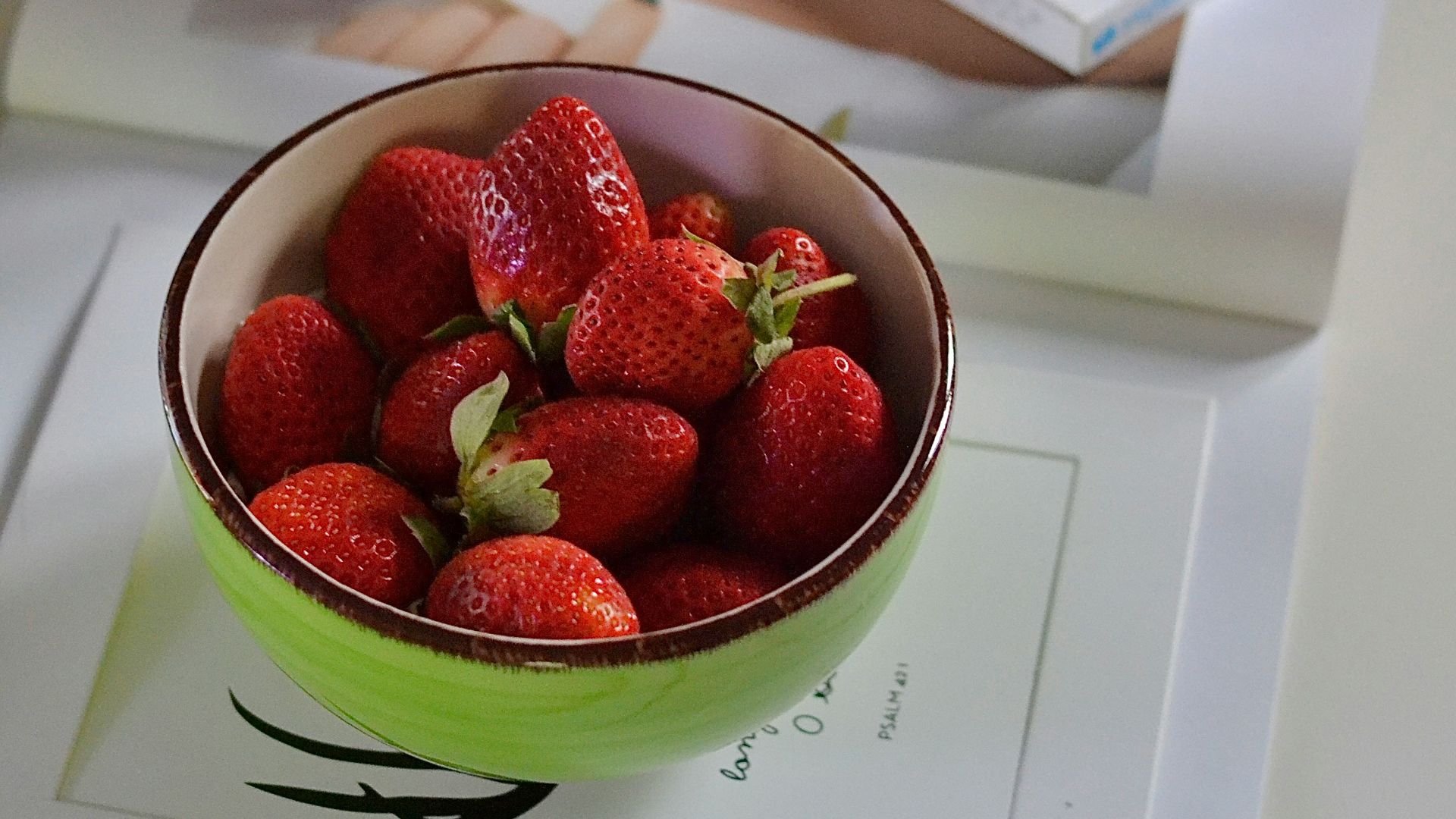 Fresh strawberries, flowers, and treats on the table.